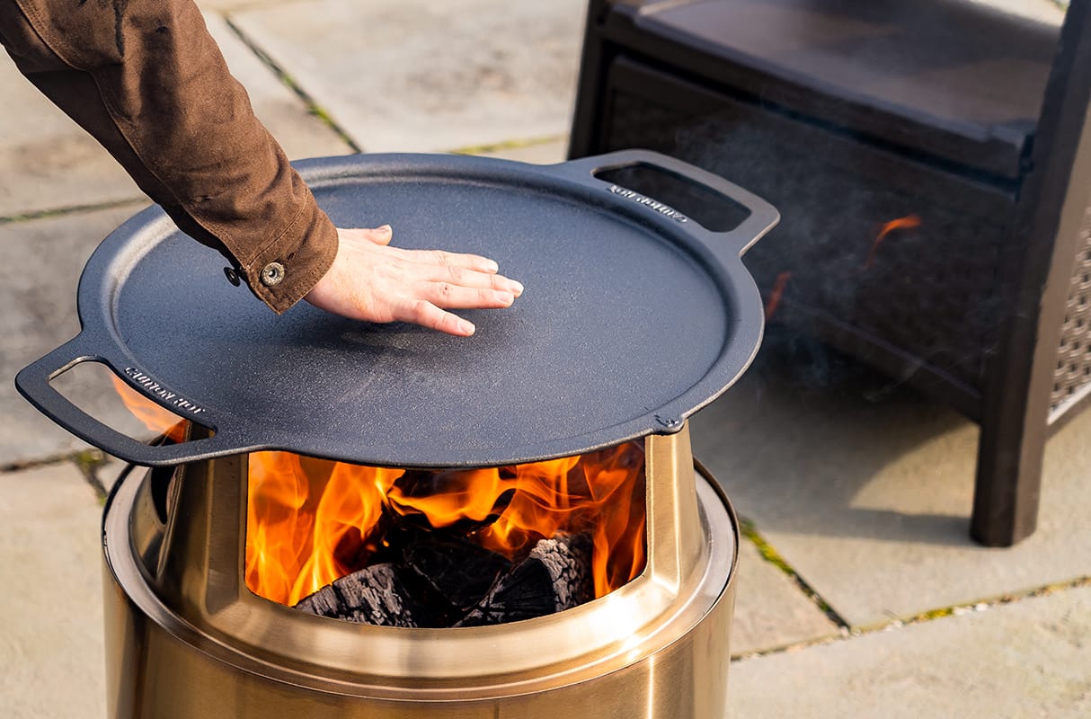 Person feeling the heat of a cooking surface over top of a fire pit